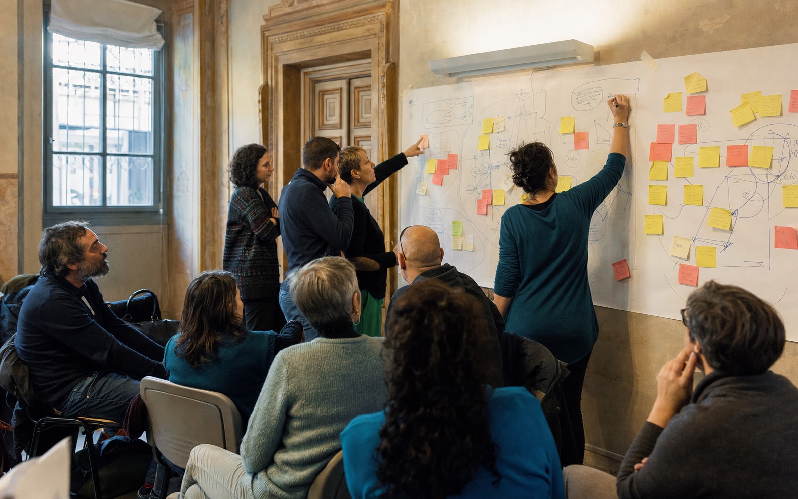 Restituzione in plenaria: idee e post-it alle pareti durante un workshop territoriale