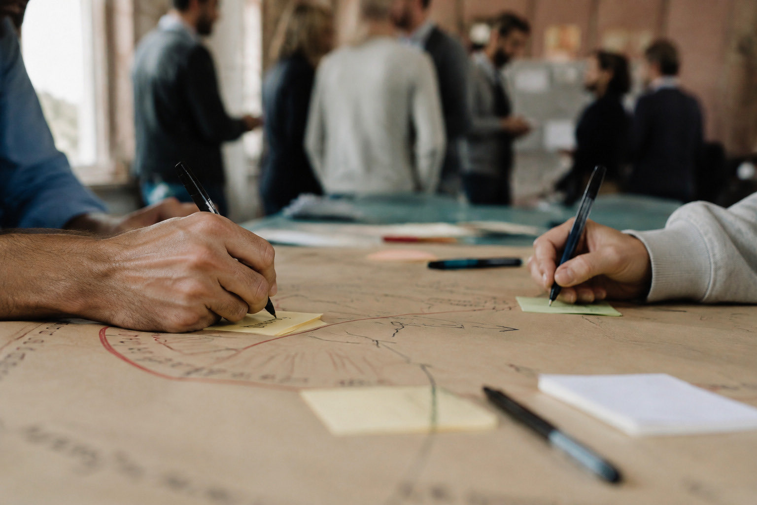 Mani che scrivono su post-it durante la costruzione condivisa di una mappa