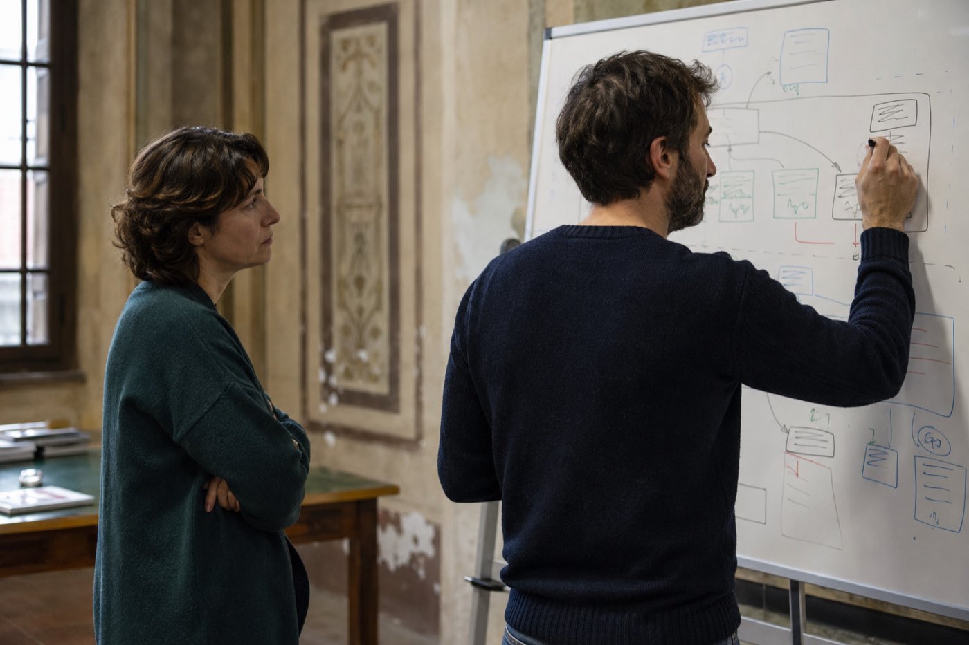 Due persone davanti a una lavagna disegnano lo schema di un’organizzazione