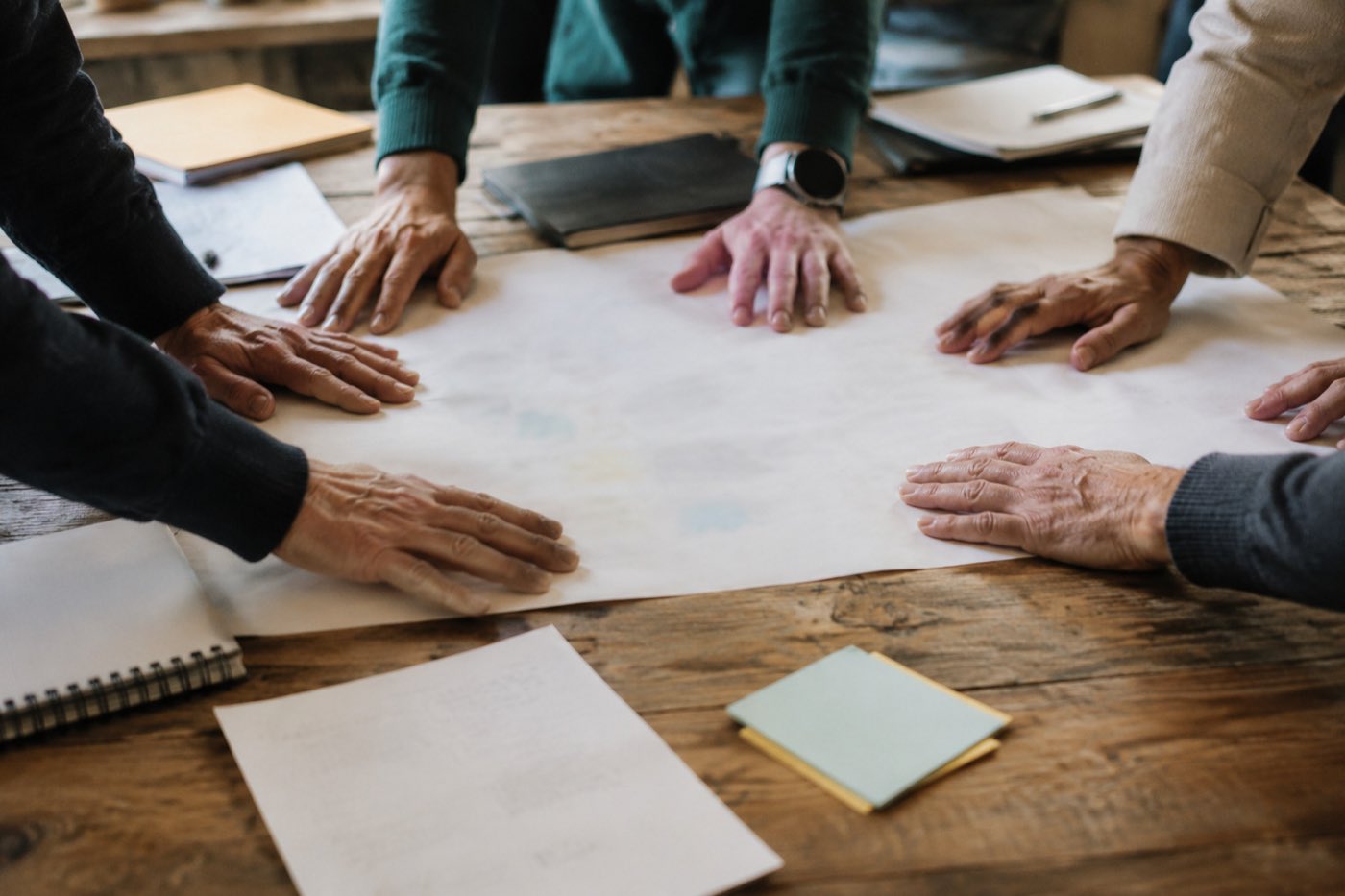Mani di più persone appoggiate insieme su un grande foglio di lavoro